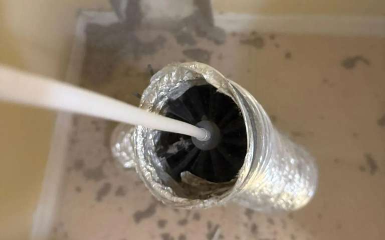 The rotary brush head inside a flexible dryer duct during a cleaning