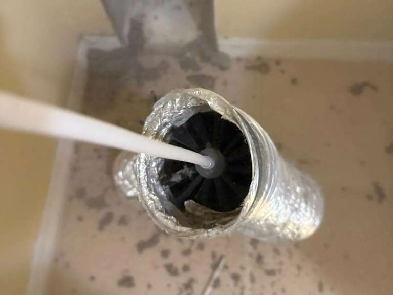 The rotary brush head inside a flexible dryer duct during a cleaning