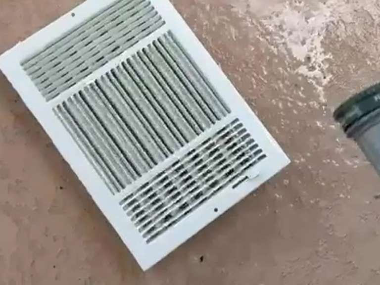 A supply register grille taken down and set on the floor during an air duct cleaning