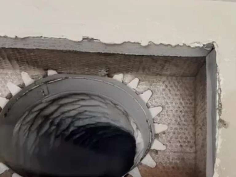 An air duct opened at a ceiling register, with the rotary brush cable inside the run