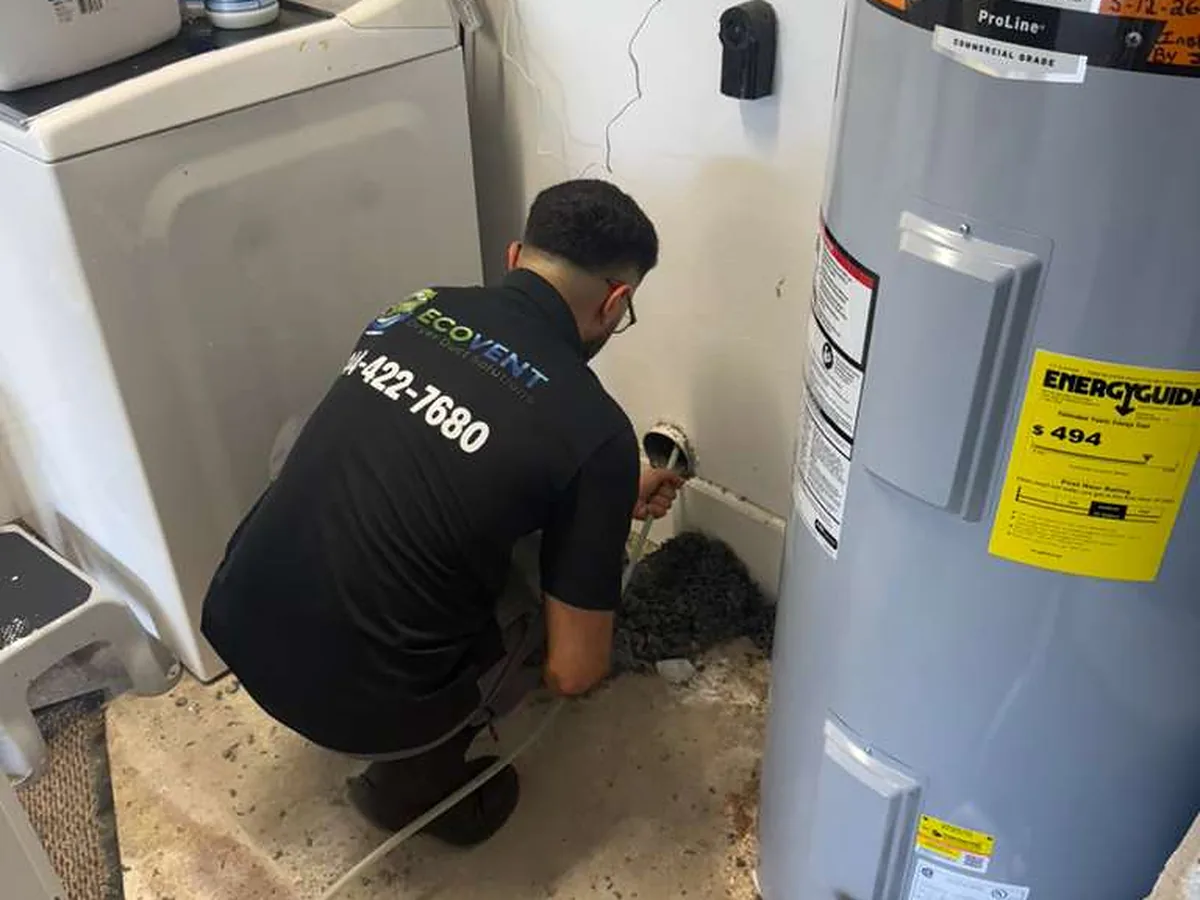 An Ecovent technician working the dryer vent connection between the washer and the water heater