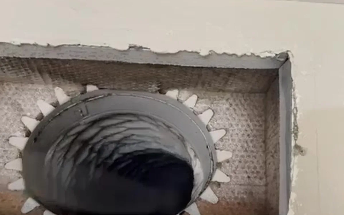 An air duct opened at a ceiling register, with the rotary brush cable inside the run
